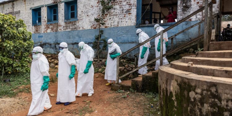 Health workers wearing protective equipment walk outside the General Referral Hospital during the Ebola outbreak response on May 21, 2026, in Mongbwalu, Democratic Republic of Congo.
