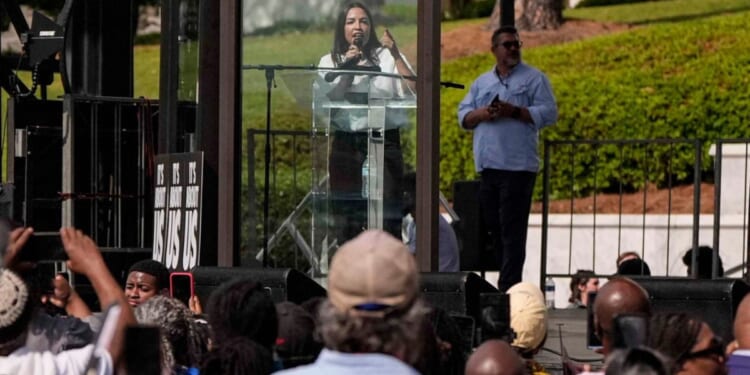 Rep. Alexandria Ocasio-Cortez, a New York Democrat, made a show of speaking from behind a bulletproof glass at a voting rights rally Saturday in Montgomery, Alabama.