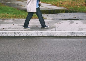 A person walks on a sidewalk during the daytime.