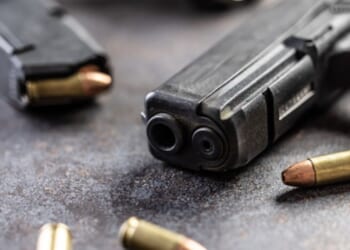 Guns and bullets lay on a table.