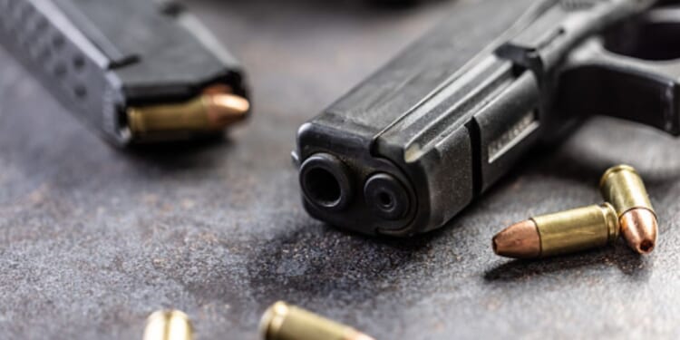 Guns and bullets lay on a table.