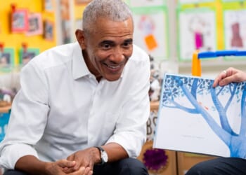 Former President Barack Obama smiling while seated