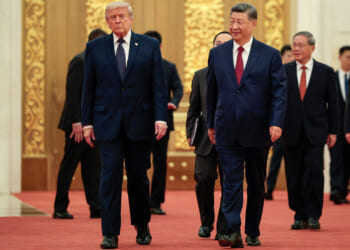 President Donald Trump and Chinese leader Xi Jinping walk together on a red carpet inside China's Great Hall.