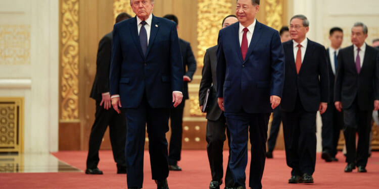 President Donald Trump and Chinese leader Xi Jinping walk together on a red carpet inside China's Great Hall.