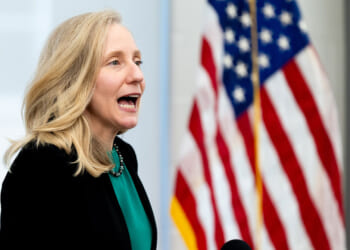 Abigail Spanberger with her mouth open, American flag in the background.