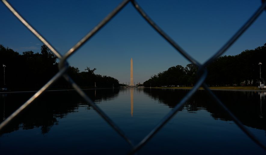 The Washington Monument, reflected in the Lincoln Memorial Reflecting Pool, is seen behind a chain link fence Thursday, June 25, 2026, in Washington. (AP Photo/Carolyn Kaster)