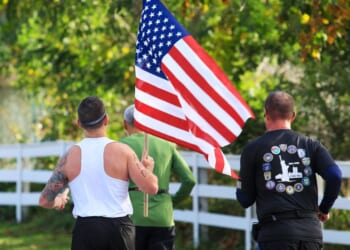 The rear view of a man carrying an American flag during a road running race in Bay Shore, New York, on Oct. 22, 2023.