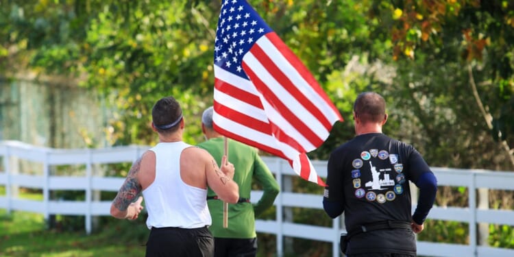 The rear view of a man carrying an American flag during a road running race in Bay Shore, New York, on Oct. 22, 2023.