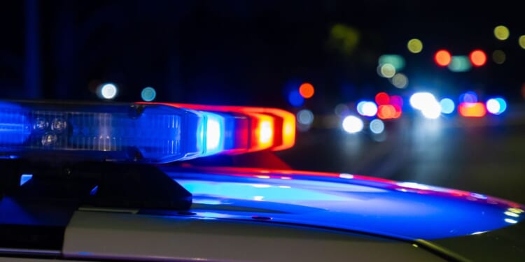 A crime scene in a city at night with blue and red police lights.