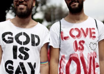 Men wearing shirts that say "God is gay" and "Love is love"