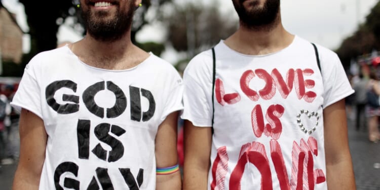 Men wearing shirts that say "God is gay" and "Love is love"