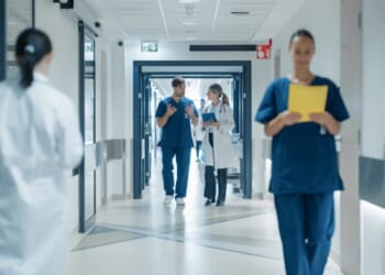 Doctors and nurses walk in a hospital hall.