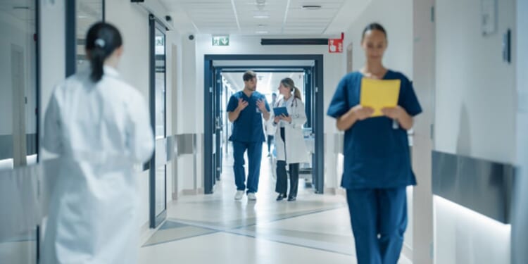 Doctors and nurses walk in a hospital hall.