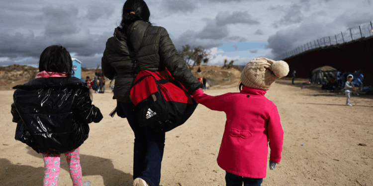 An immigrant and her two daughters walk along the U.S. Mexico Border.