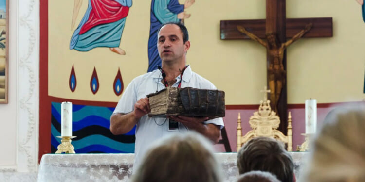 Shadi Khalloul presents an ancient Aramean Bible while speaking to a group of students at the Syriac Maronite Church of Antioch in Jish.
