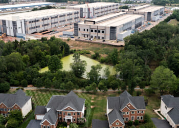 In an aerial view, an Amazon Web Services data center is shown situated near single-family homes on July 17, 2024 in Stone Ridge, Virginia.