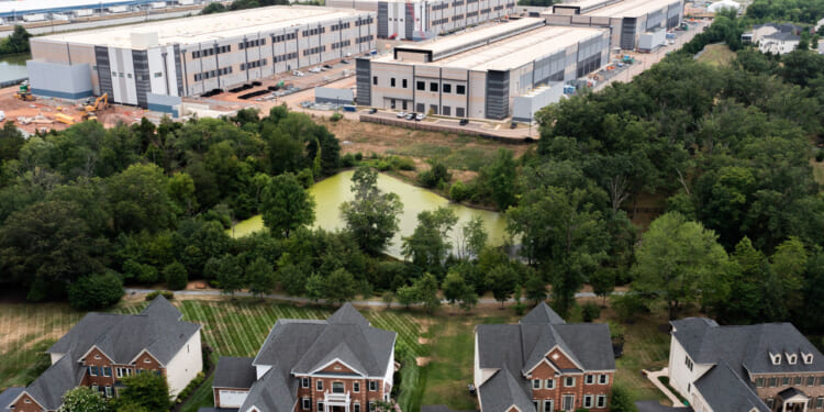 In an aerial view, an Amazon Web Services data center is shown situated near single-family homes on July 17, 2024 in Stone Ridge, Virginia.