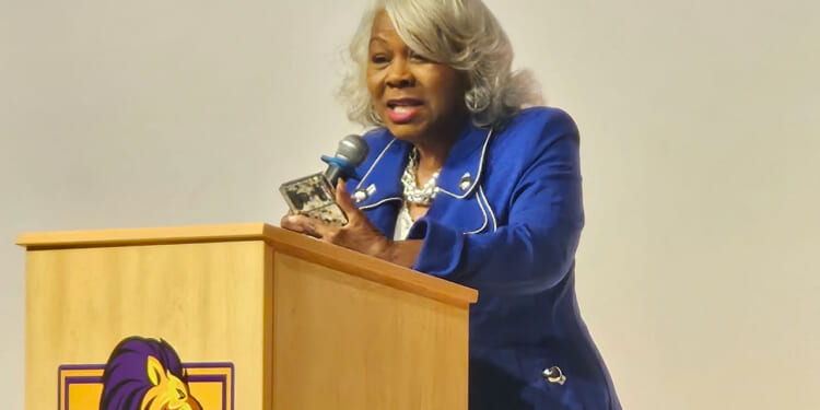 Virginia President Pro Tempore L. Louise Lucas speaks at a tan podium.