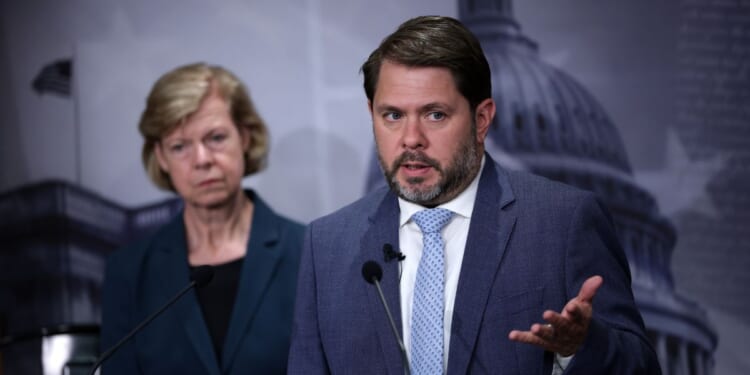 Sen. Tammy Baldwin listens as Sen. Ruben Gallego speaks during a news conference to introduce the Protect our Polls Act at the U.S. Capitol on June 18, 2026, in Washington, D.C.
