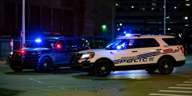 Two Detroit police vehicles flash their lights in the street on Dec. 20, 2020.
