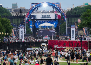 Crowd gathered for Freedom 250 event, with red, white and blue stage in the background.