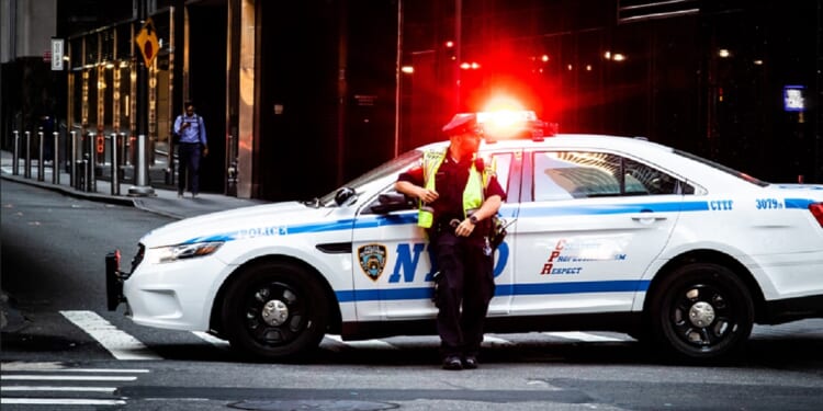 A New York City police officer is pictured in a May 2019 file photo with his patrol vehicle's lights flashing.