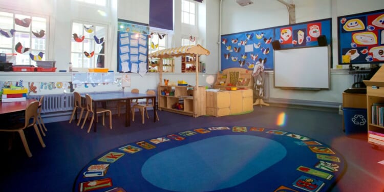 An image of an empty nursery classroom with a rug in the middle of the floor.