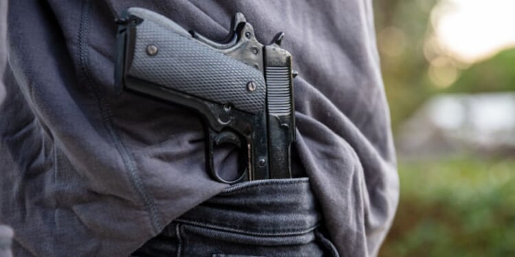 Man carries gun in his pants as he walks in a field.