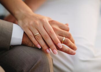 A groom and a bride hold hands.
