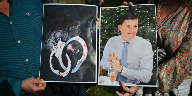 People hold images of victim Henry Nowak, and blood-covered handcuffs as they take part in a protest outside of Southampton Central Police Station in Southampton, southern England, on June 2, 2026, following the murder of Henry Nowak by Vickrum Digwa. Body camera footage of a dying student who was handcuffed by British police after being stabbed by a Sikh man and falsely accused of racially abusing his murderer sparked outrage Tuesday. (Photo by JUSTIN TALLIS / AFP via Getty Images)