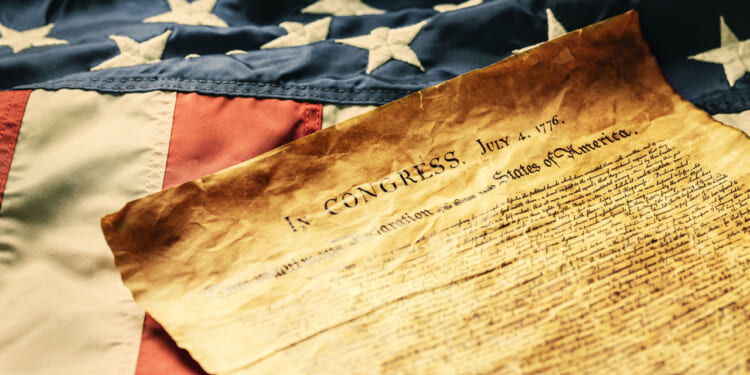 The Declaration of Independence laying upon an old American flag.