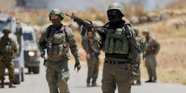 Israeli soldiers walk near a roadside fence in the occupied West Bank on June 5, 2026.
