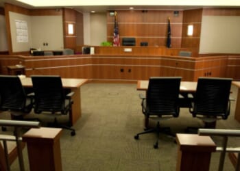 A modern courtroom sits empty under dim lights.