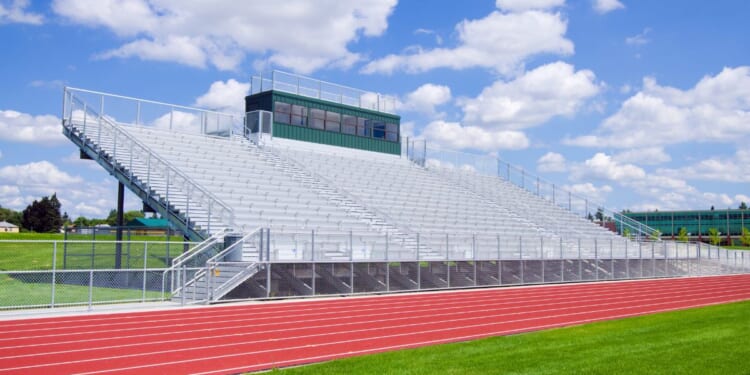 Bleachers at a high school football field with track.