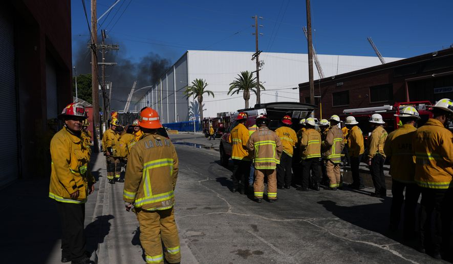 Fire crews stage outside a warehouse in the Boyle Heights section of Los Angeles on Wednesday, June 17, 2026. (AP Photo/Jae C. Hong)