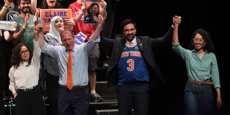 Claire Valdez, Brad Lander, Mayor Zohran Mamdani, and Darializa Avila Chevalier raise their hands on stage during a rally.