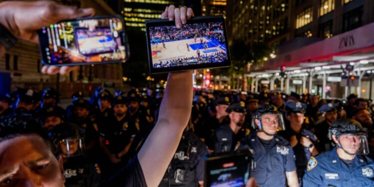 A Knicks fan holds up a screen of the NBA finals game between New York City and San Antonio at a watch party in Bryant Park for Game 3 of the Finals in New York City on June 8, 2026.
