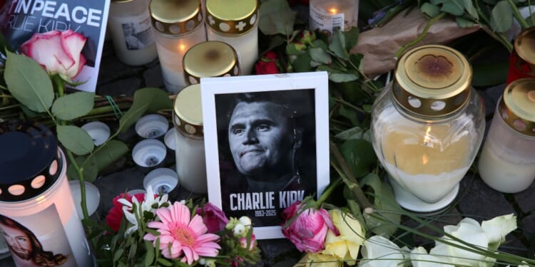 Flowers and candles are seen at a makeshift memorial for murdered American conservative activist Charlie Kirk outside the U.S. embassy as its flag hangs at half-staff on Sept. 14, 2025, in Berlin, Germany.