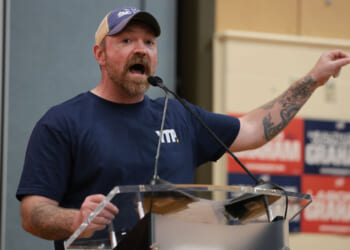 Senate candidate Graham Platner gestures with his arm out as he speaks at an event.