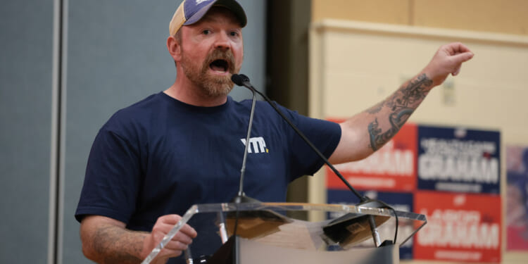 Senate candidate Graham Platner gestures with his arm out as he speaks at an event.