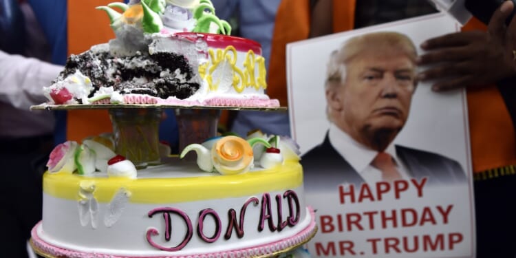 Supporters stand with a birthday cake to celebrate President Trump's birthday.