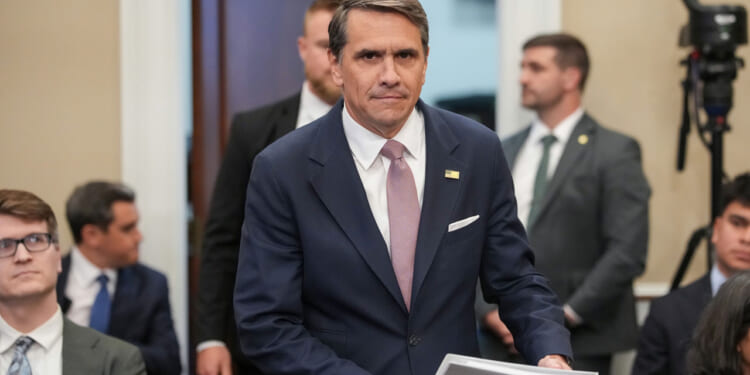 Acting Attorney General Todd Blanche looks right at the camera as he arrives for a hearing with files in his hand.