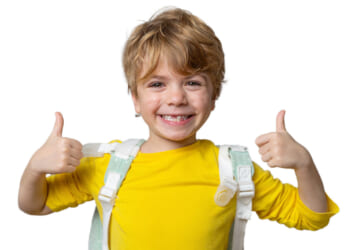 Smiling boy in yellow shirt with backpack over his shoulders gives two thumb's up.