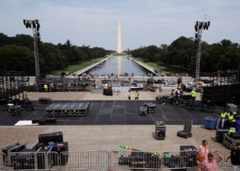 With the Washington Monument and the Reflecting Pool of the National Mall in the background, workers construct a stage for part of the upcoming Ultimate Fighting Championship Freedom 250 event in Washington.