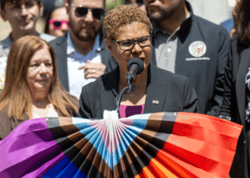 Los Angeles Mayor Karen Bass stands at a podium draped with pride colors.