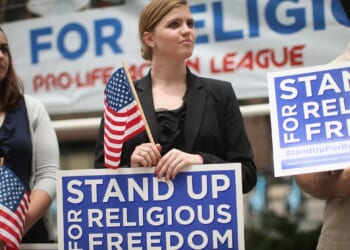 People holding signs that say "stand up for religious freedom"