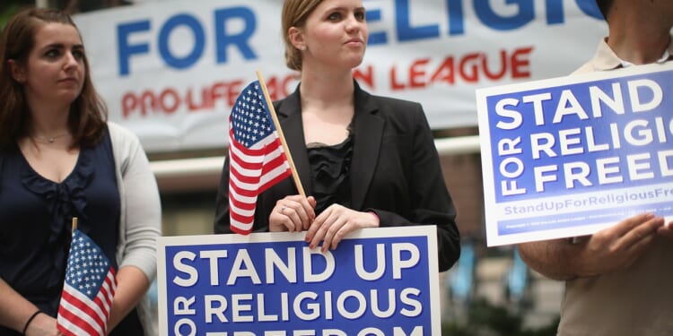 People holding signs that say "stand up for religious freedom"