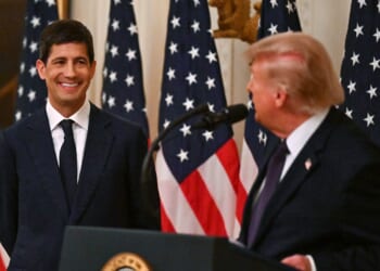 Donald Trump and Kevin Warsh in front of several American flags.