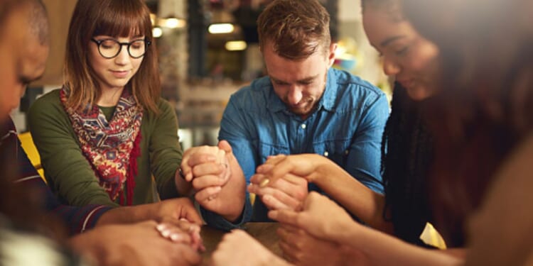 A group of people pray in a circle.