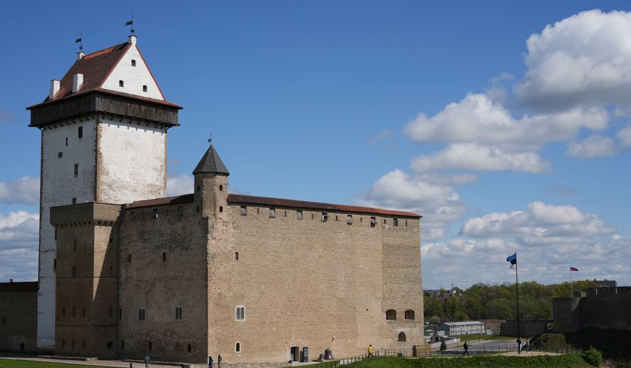 Both the Estonian and Russian flags fly in the breeze atop their ancient forts on either side of the Narva River, the border between the two countries. Viewed from the Narva Museum and Castle. (John T. Seward/The Washington Times)
